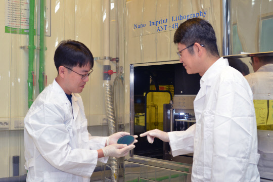 표준연 연구자들이 반도체 소자 제작 공정 기술을 기반으로 달걀 프라이 형태의 금 나노입자를 합성한 웨이퍼 표면을 관찰하고 있다.  표준연 제공